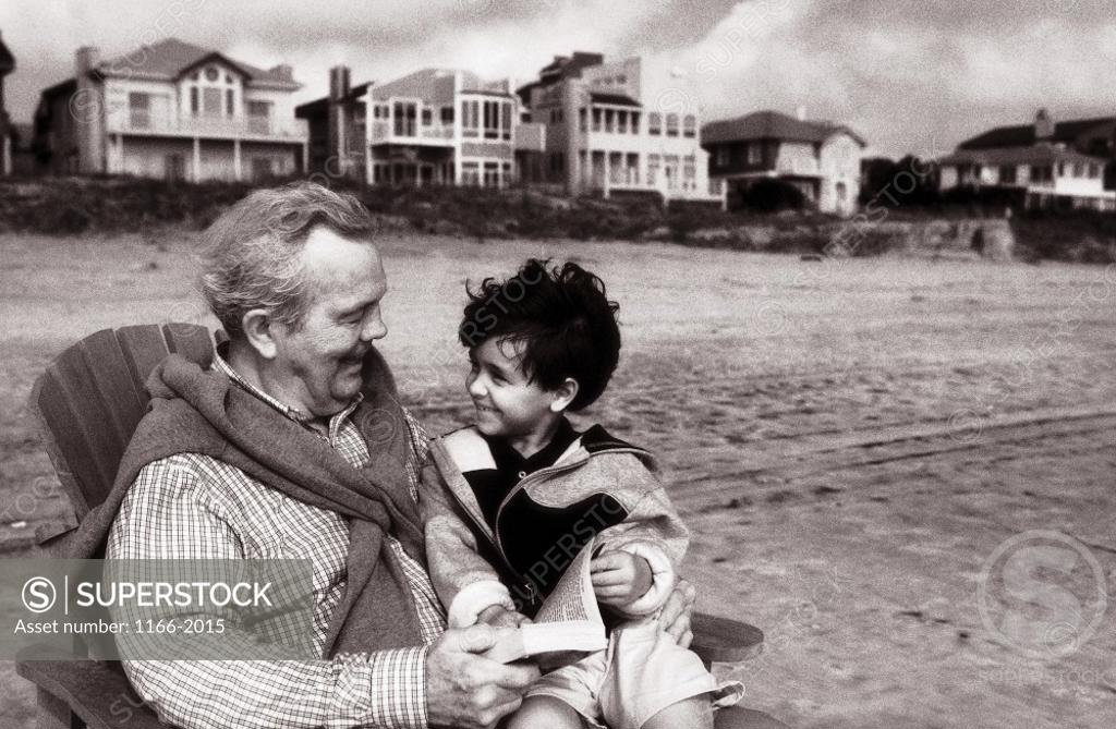 Stock Photo: 1166-2015 A child sitting with his grandfather on the beach