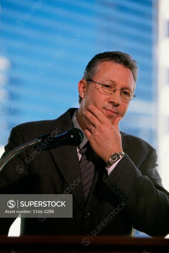 Stock Photo: 1166-2288 Close-up of a businessman standing in front of a microphone at a podium