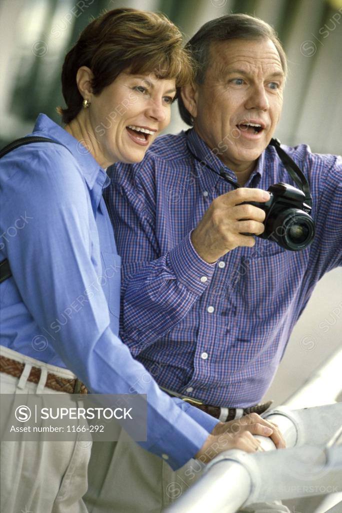 Stock Photo: 1166-292 Mature couple on a cruise ship with a camera