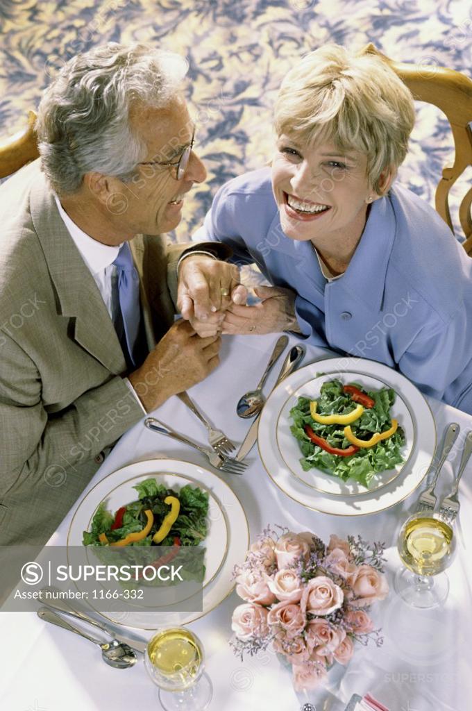 Stock Photo: 1166-332 Portrait of a senior woman holding a senior mans hands at a dining table