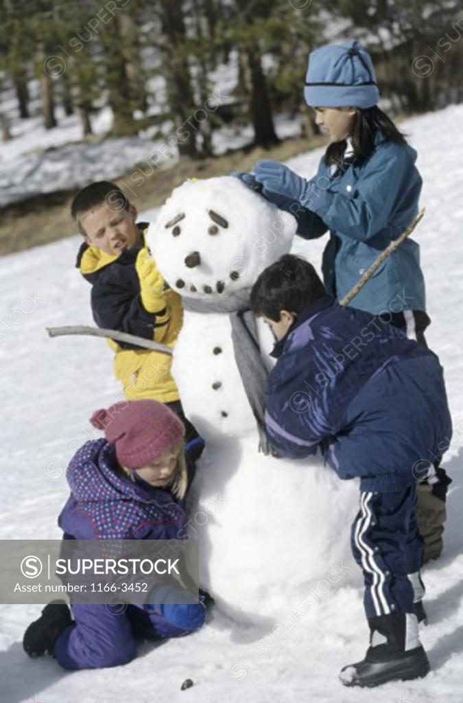 Stock Photo: 1166-3452 Two boys and two girls building a snowman