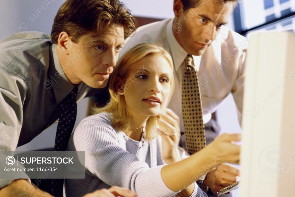 Stock Photo: 1166-354 Two businessmen and a businesswoman in front of a computer monitor