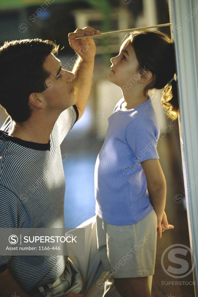 Stock Photo: 1166-446 Side profile of a father measuring his daughter's height