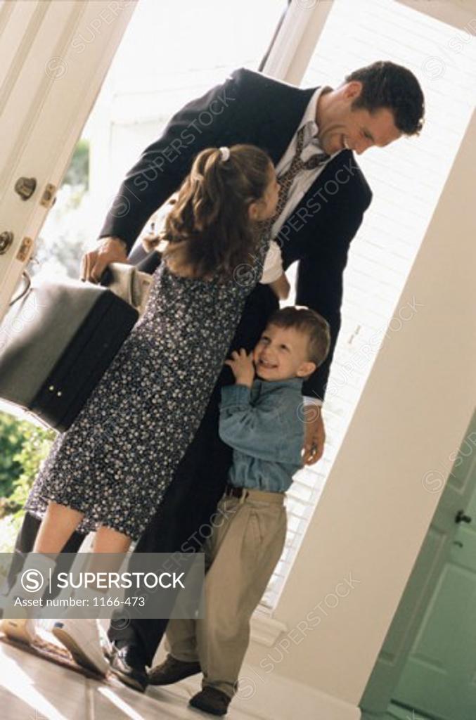 Stock Photo: 1166-473 Boy and girl hugging their father in a doorway