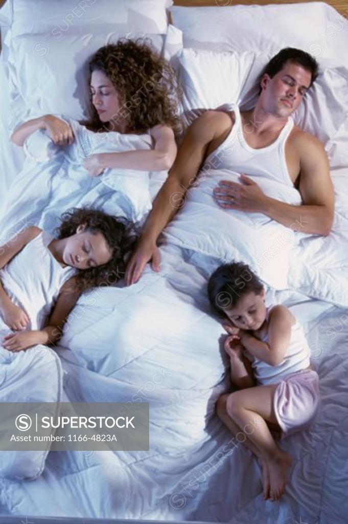 Stock Photo: 1166-4823A Mid adult couple sleeping with their son and daughter on a bed