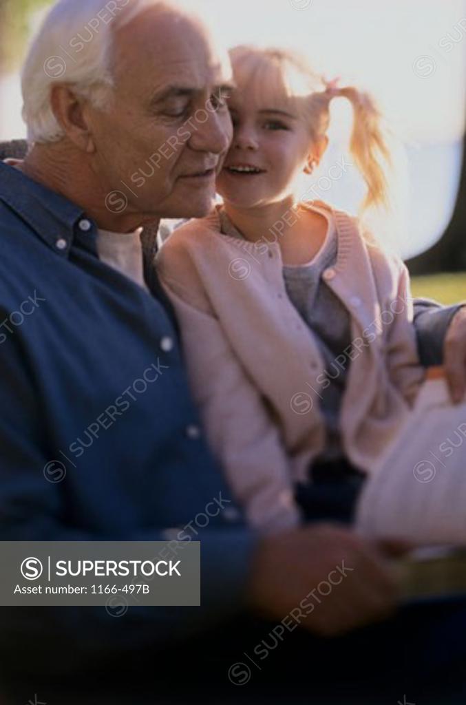 Stock Photo: 1166-497B Senior man reading a book with his granddaughter