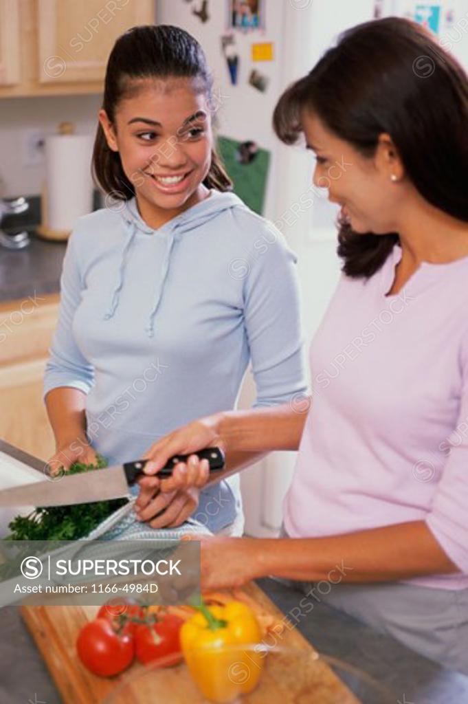 Stock Photo: 1166-4984D Teenage girl with her mother cooking in a kitchen