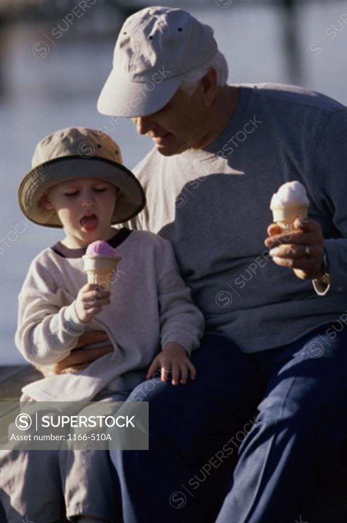 Stock Photo: 1166-510A Grandfather sitting with his grandson holding ice cream cones
