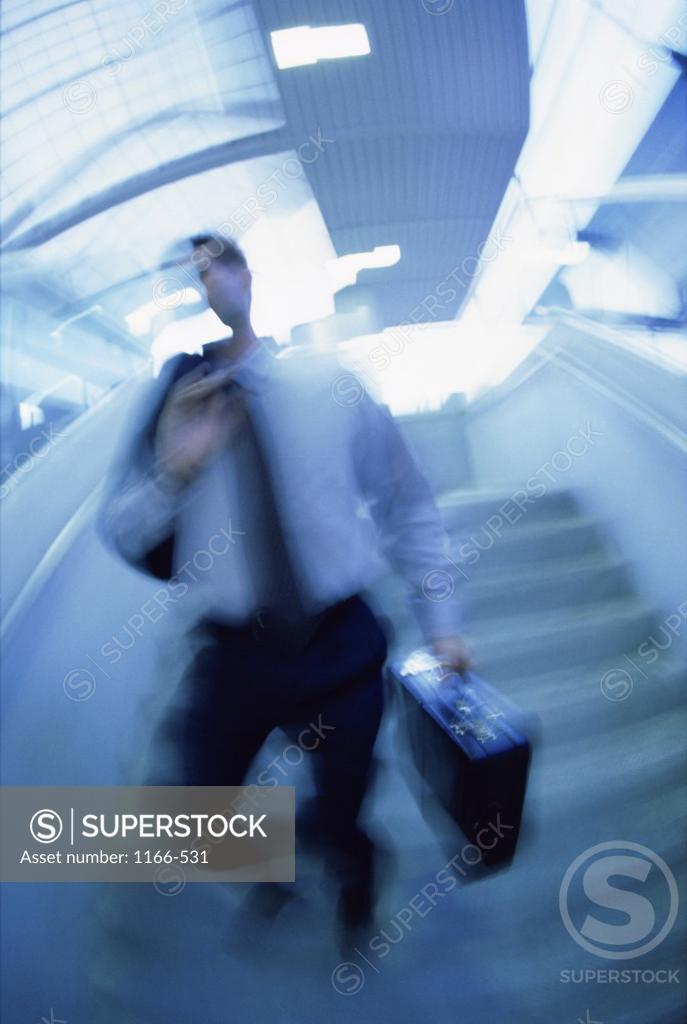 Stock Photo: 1166-531 Businessman walking down a staircase with a briefcase