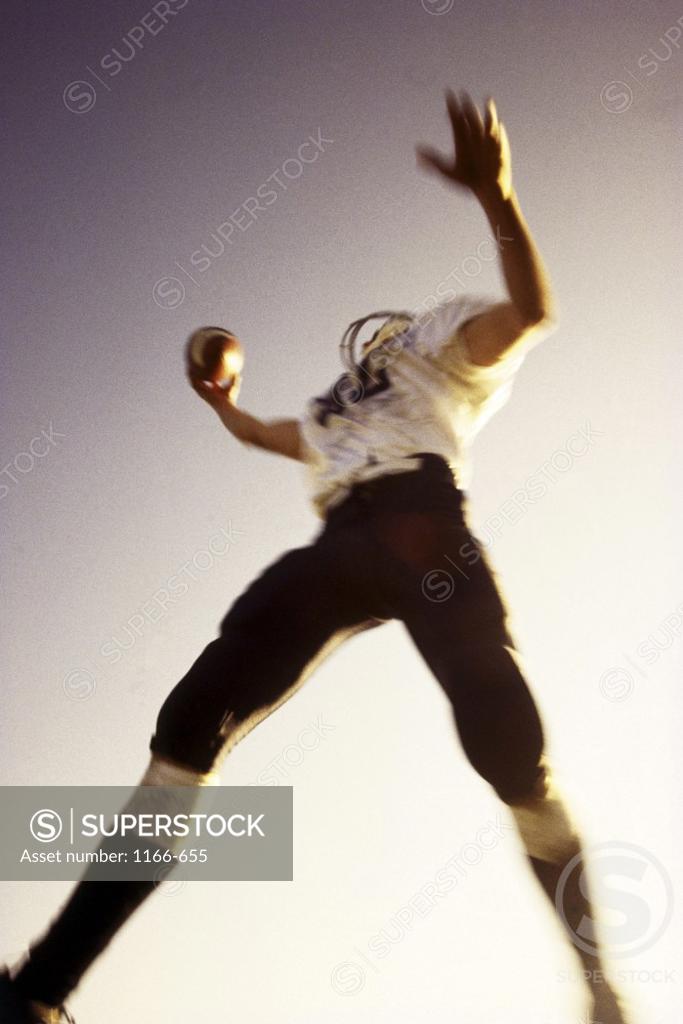 Stock Photo: 1166-655 High angle view of a football player jumping in the air with a football