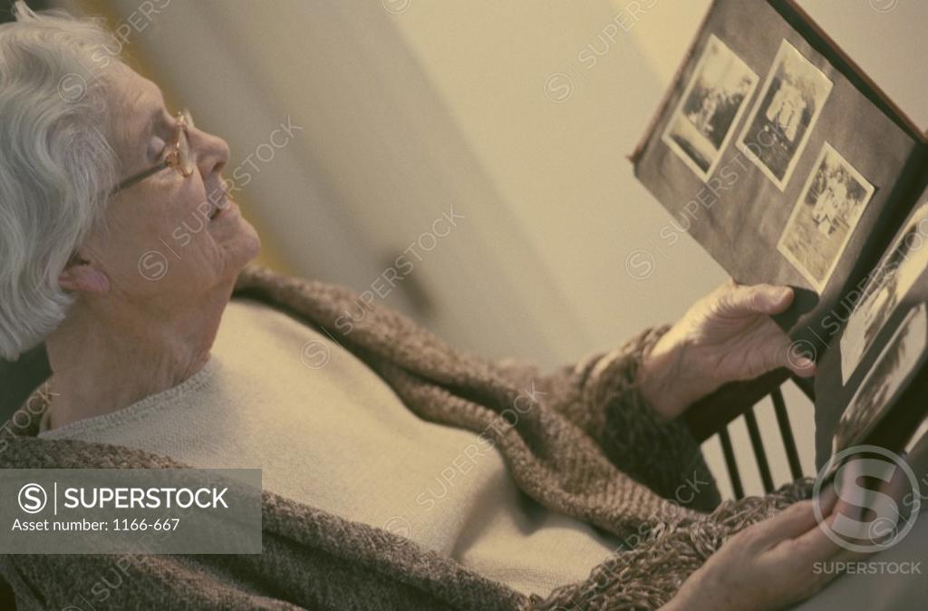 Stock Photo: 1166-667 Senior woman looking at a photo album