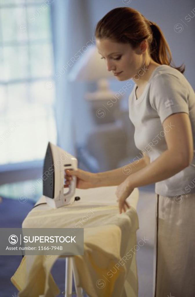 Stock Photo: 1166-794B Young woman ironing a shirt