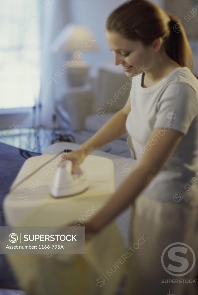 Stock Photo: 1166-795A Young woman ironing a shirt