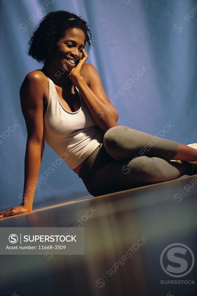 Stock Photo: 1166R-3509 Young woman sitting on the floor smiling