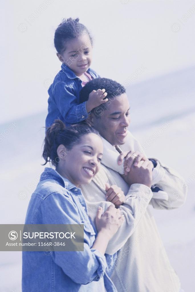 Stock Photo: 1166R-3846 Father and mother walking on the beach carrying their daughter