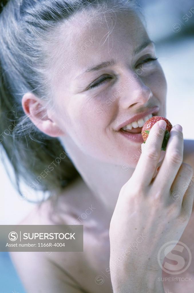 Stock Photo: 1166R-4004 Young woman eating a strawberry
