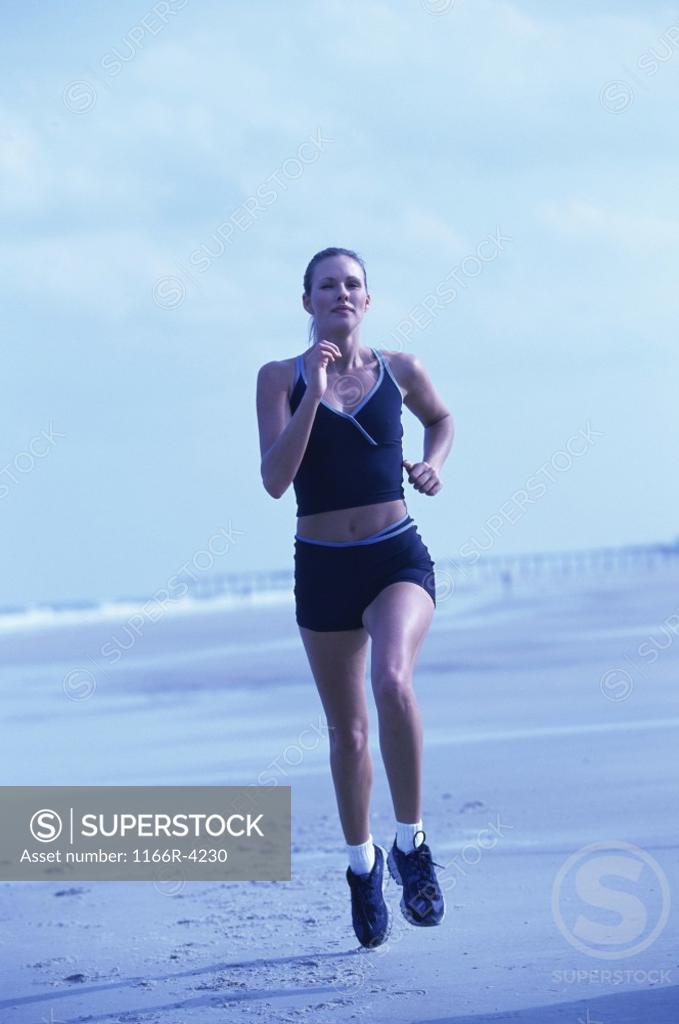 Stock Photo: 1166R-4230 Portrait of a young woman running on the beach
