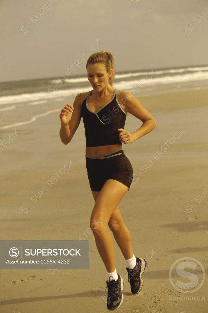 Stock Photo: 1166R-4232 Young woman running on the beach