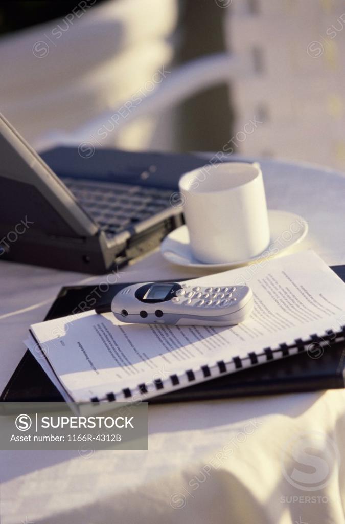 Stock Photo: 1166R-4312B Mobile phone on a notebook near a cup of coffee and a laptop