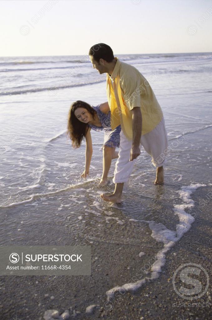Stock Photo: 1166R-4354 Young couple playing at the beach