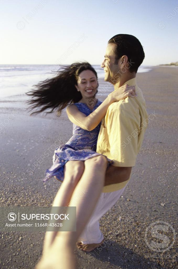 Stock Photo: 1166R-4362B Young man carrying a young woman on the beach