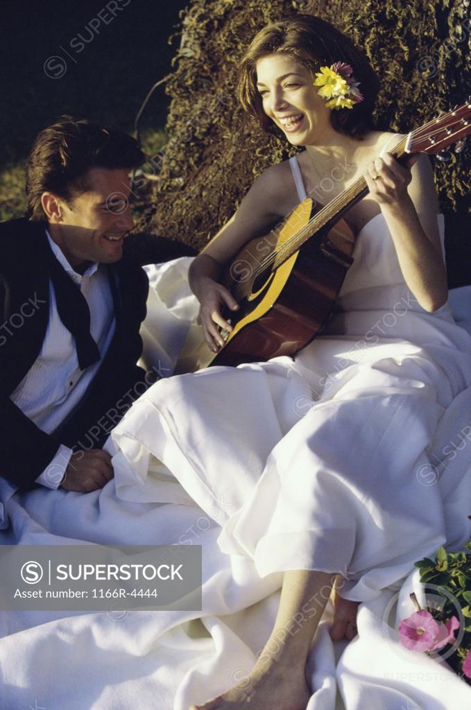 Stock Photo: 1166R-4444 Bride and groom sitting together playing a guitar