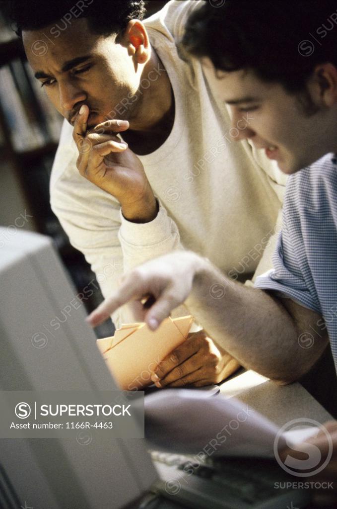 Stock Photo: 1166R-4463 Two young men looking at a computer monitor