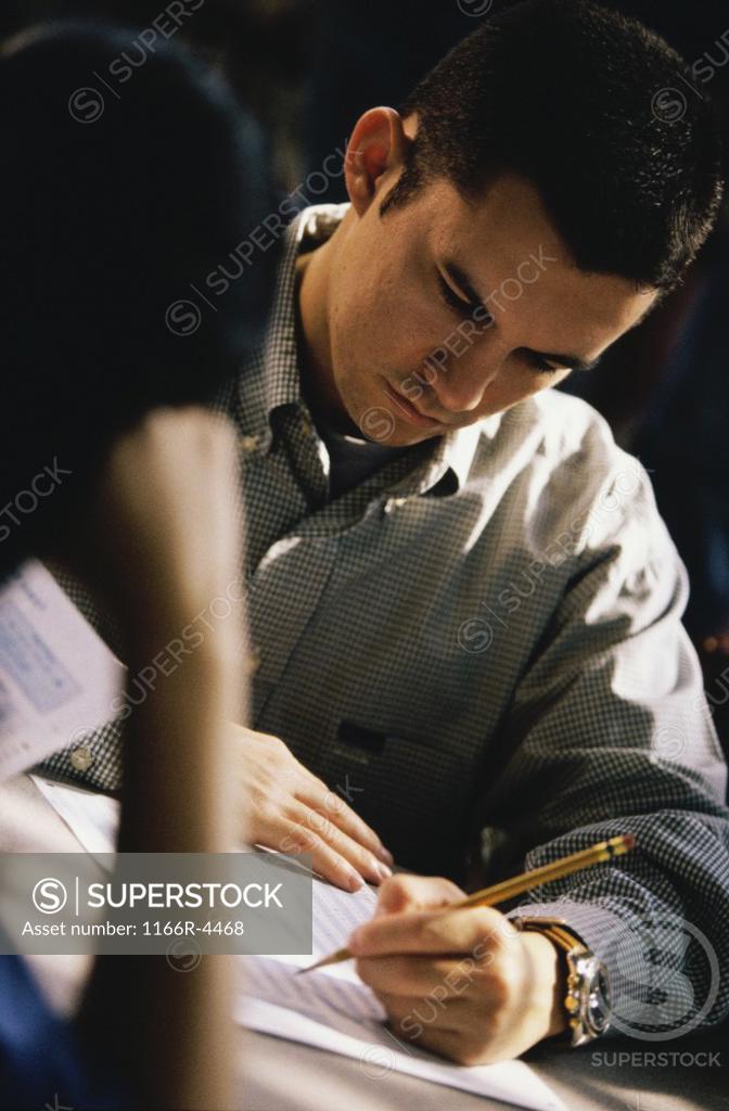 Stock Photo: 1166R-4468 Male student writing during an examination