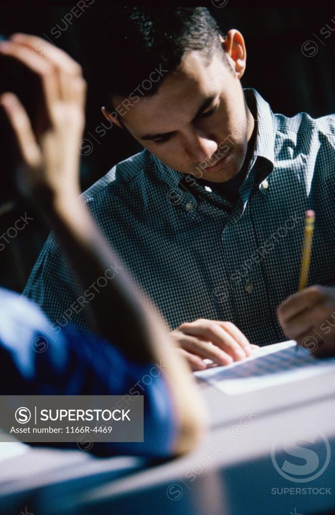 Stock Photo: 1166R-4469 Male student writing during an examination