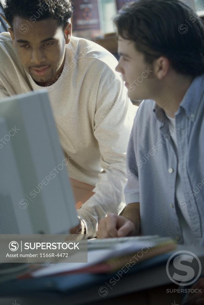 Stock Photo: 1166R-4472 Two young men looking at a computer monitor