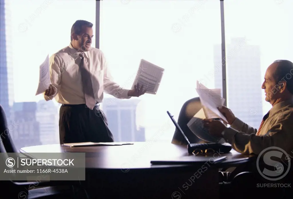 Two businessmen holding documents in an office