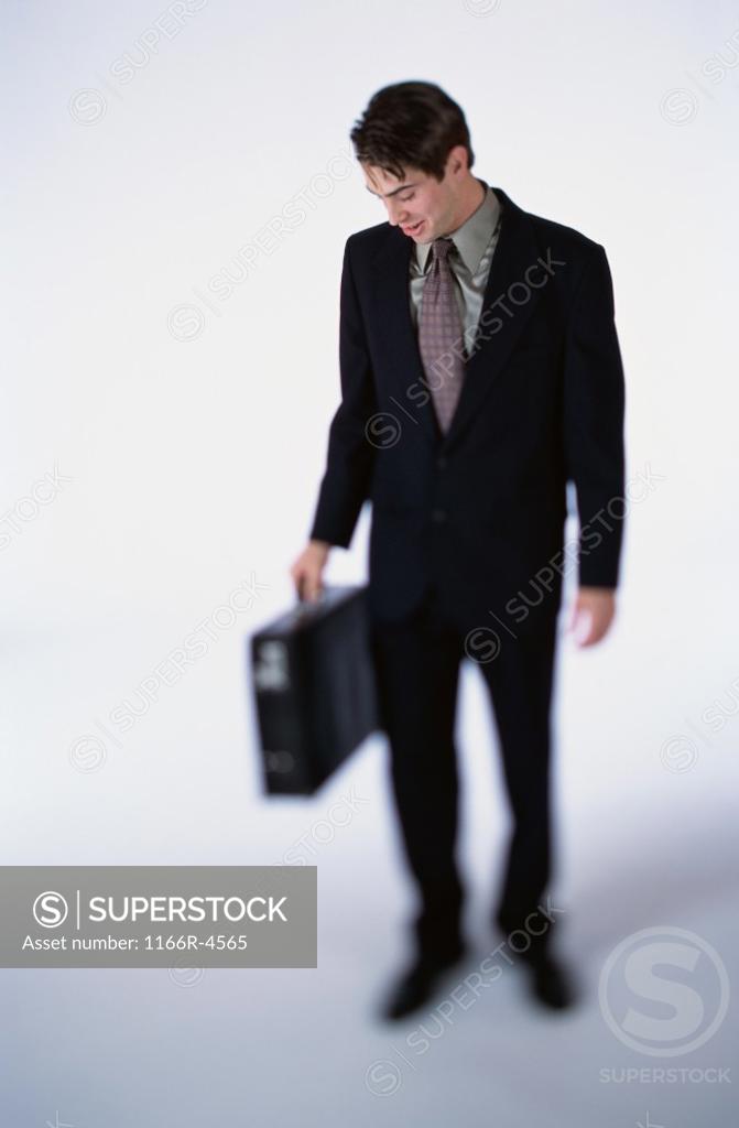 Stock Photo: 1166R-4565 Businessman looking down while holding a briefcase