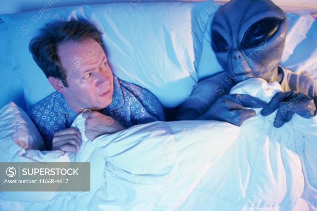Stock Photo: 1166R-4617 Man lying in bed with an alien