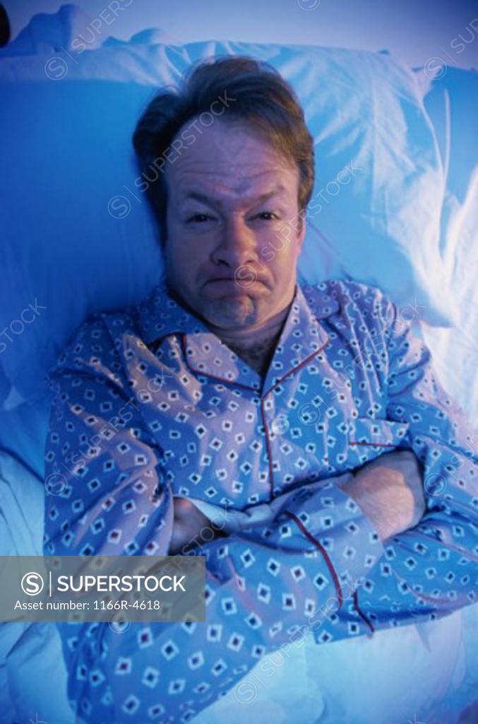 Stock Photo: 1166R-4618 Portrait of a man lying in the bed pouting