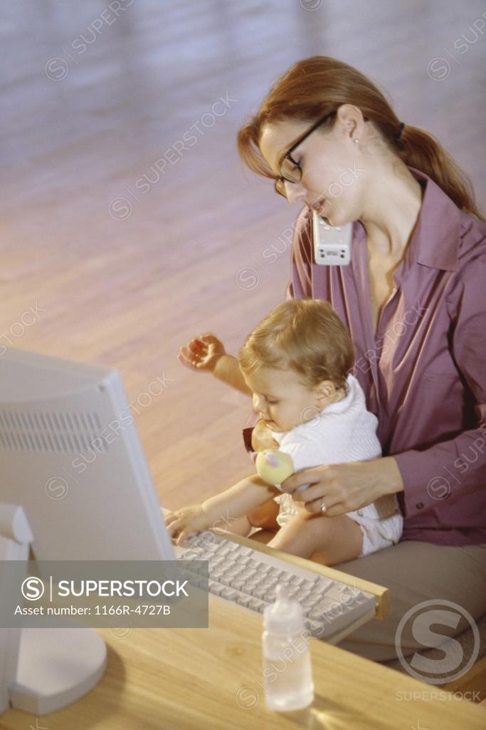 Stock Photo: 1166R-4727B Mother talking on a telephone holding her baby girl