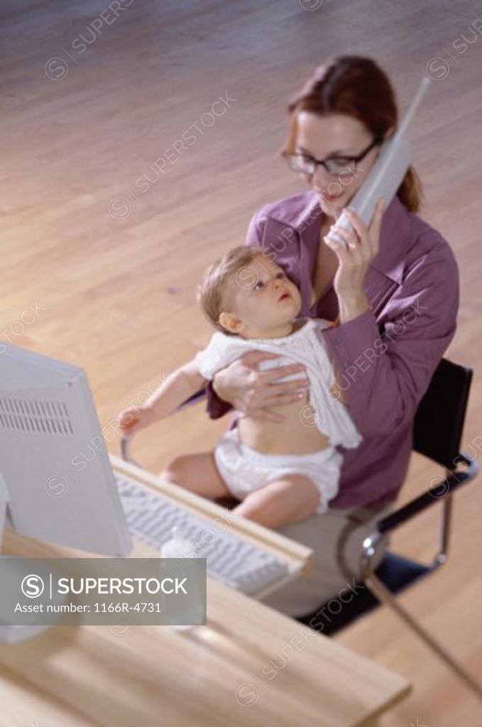 Stock Photo: 1166R-4731 Mother talking on a telephone holding her baby girl
