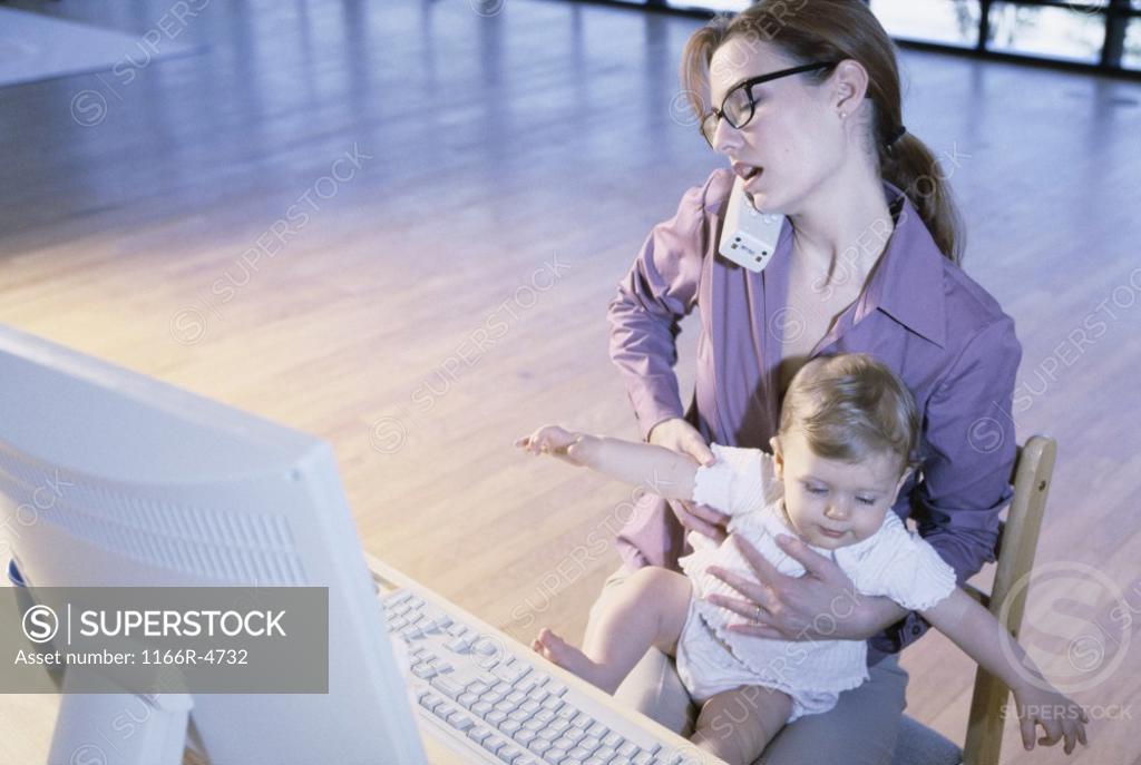 Stock Photo: 1166R-4732 Mother talking on a telephone holding her baby girl