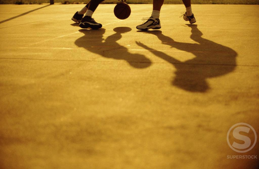 Low section view of two people playing basketball