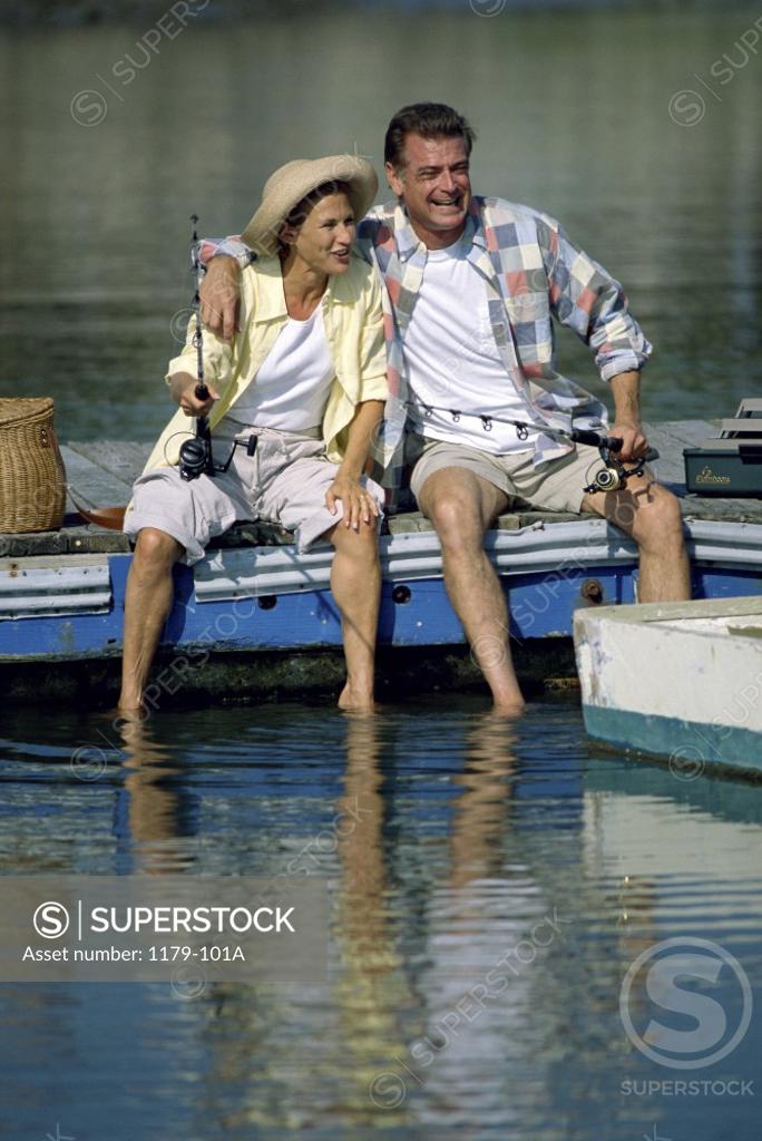 Stock Photo: 1179-101A Mid adult couple sitting on a pier holding fishing rods