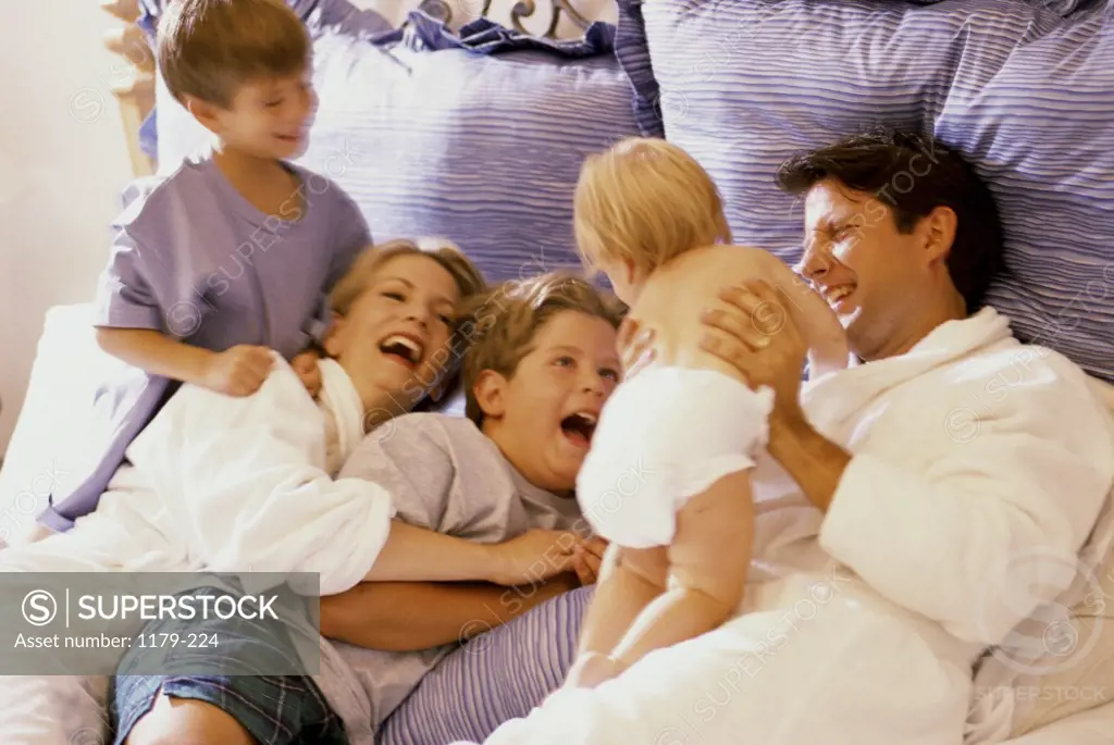 Parents playing with their children on a bed