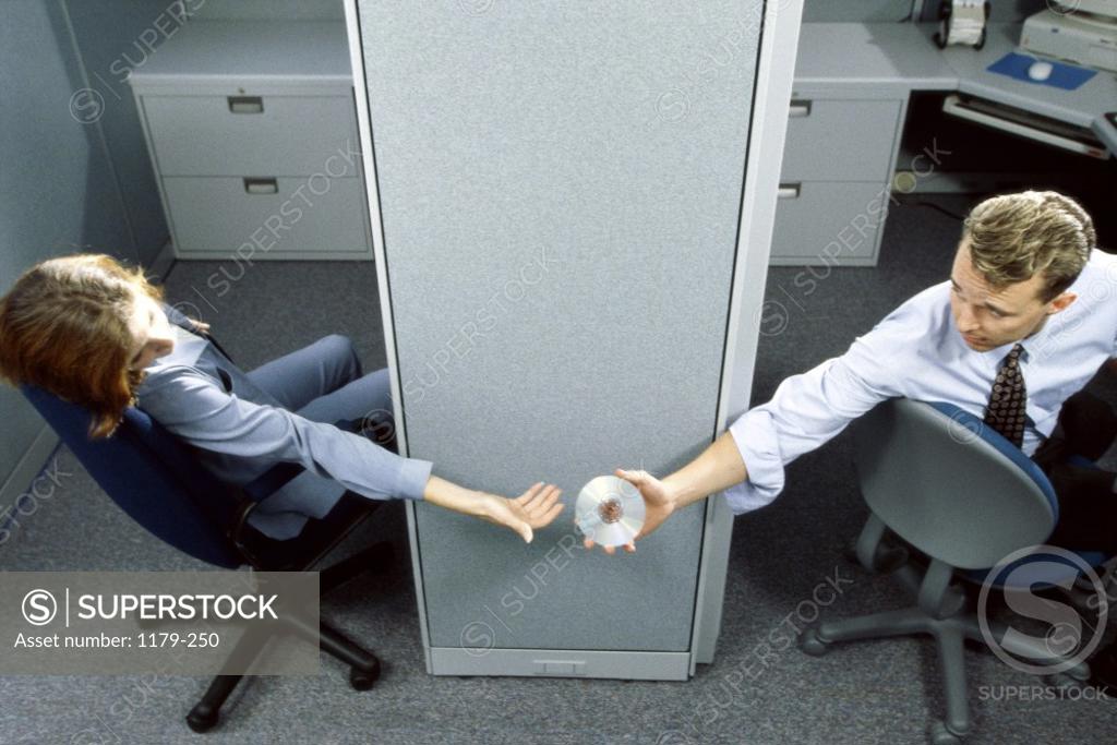 Stock Photo: 1179-250 Businessman handing a compact disk to a businesswoman in an office