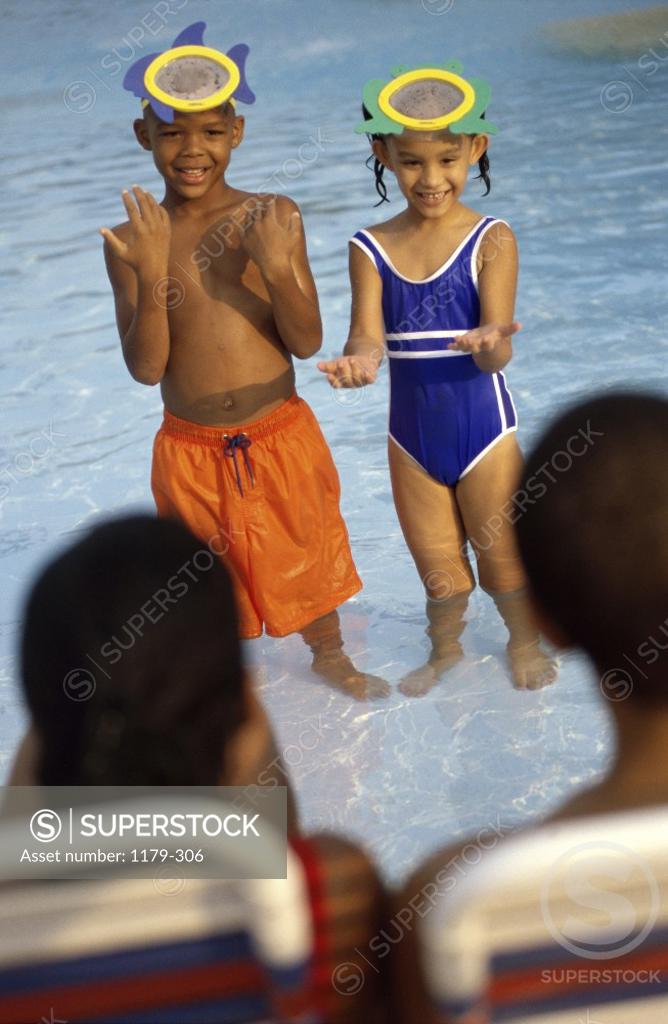 Stock Photo: 1179-306 Boy and a girl standing in a swimming pool in front of their parents