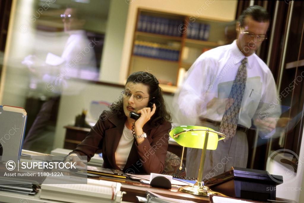 Stock Photo: 1180-122A Businesswoman talking on the telephone with a businessman standing beside her