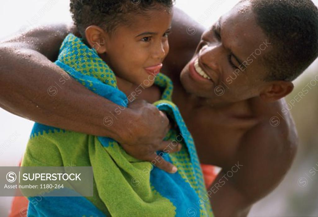 Stock Photo: 1180-264 Mid adult man hugging his son on the beach