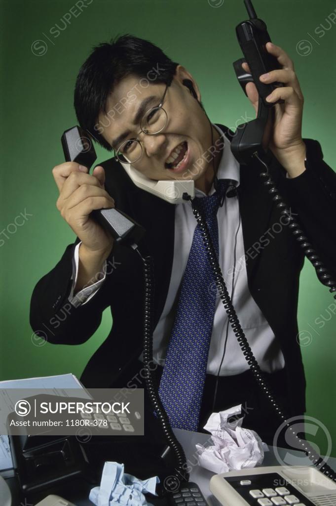 Stock Photo: 1180R-378 Businessman holding telephone receivers