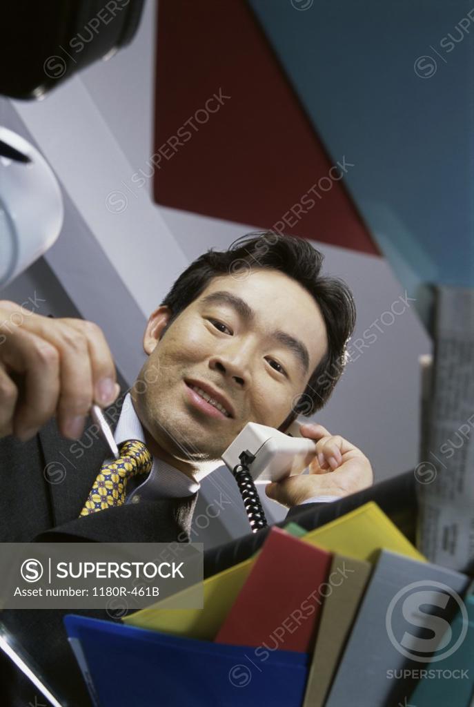 Stock Photo: 1180R-461B Low angle view of a businessman talking on landline telephone