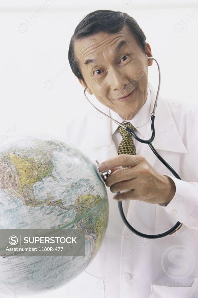 Stock Photo: 1180R-477 Portrait of a male doctor holding a stethoscope on a globe