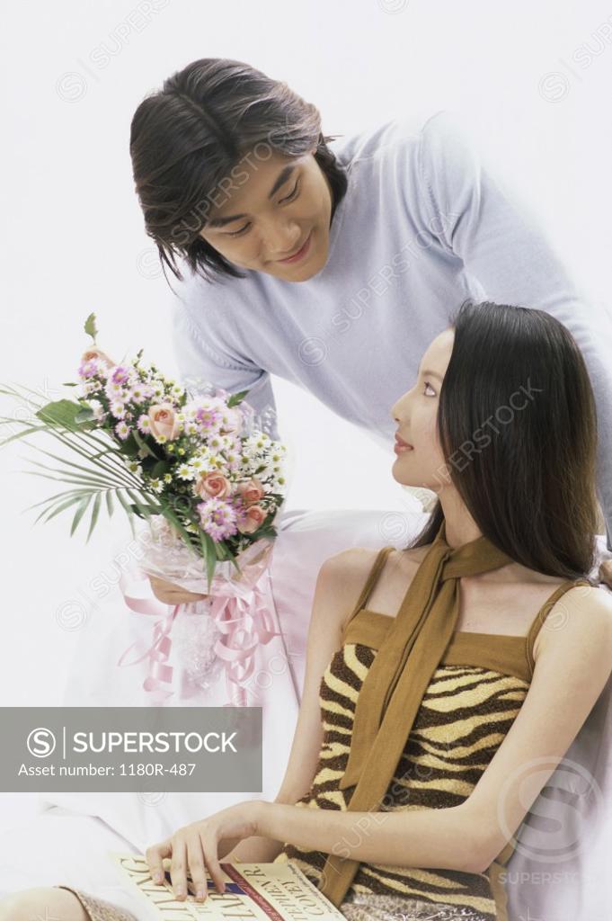 Stock Photo: 1180R-487 Young man presenting a young woman with a bouquet of flowers