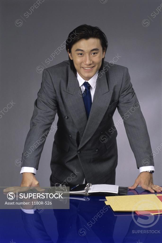 Stock Photo: 1180R-526 Portrait of a businessman standing behind an office desk