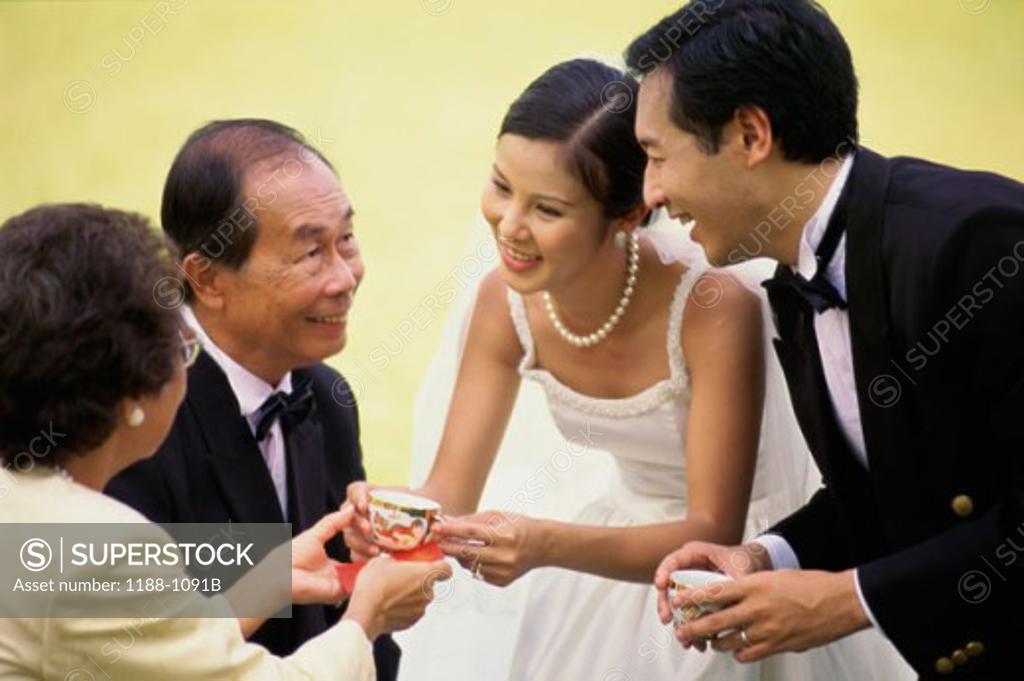 Stock Photo: 1188-1091B Newlywed couple offering tea to their parents